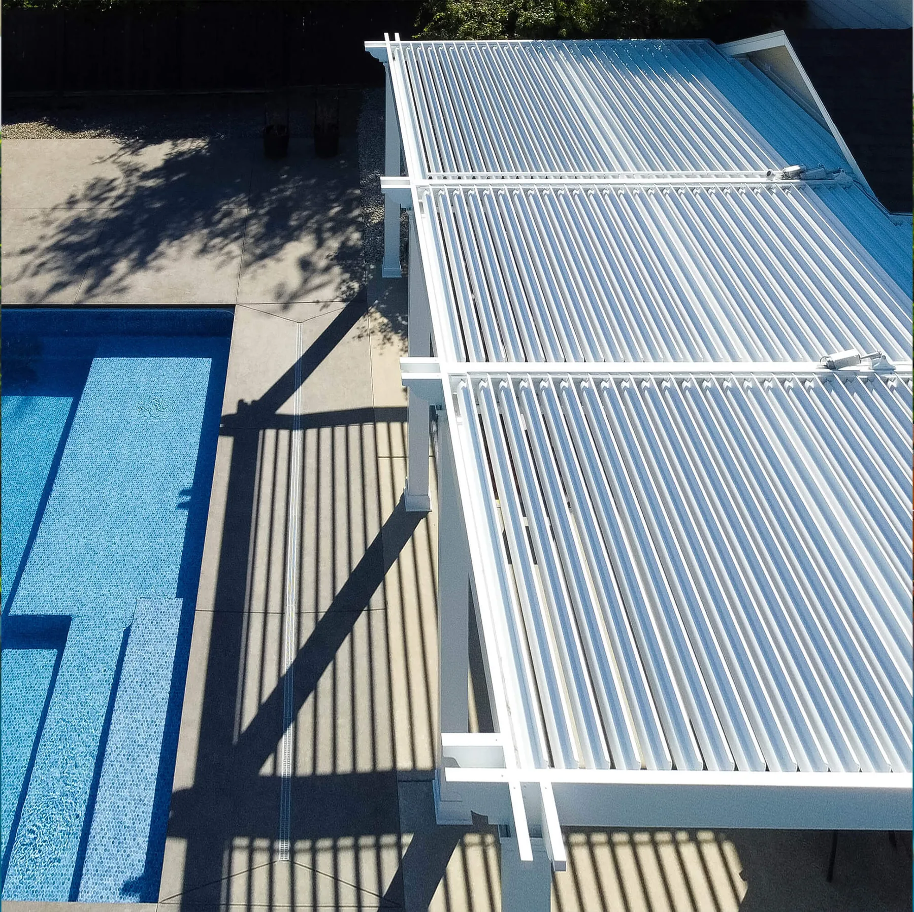 White louvered pergola beside a pool
